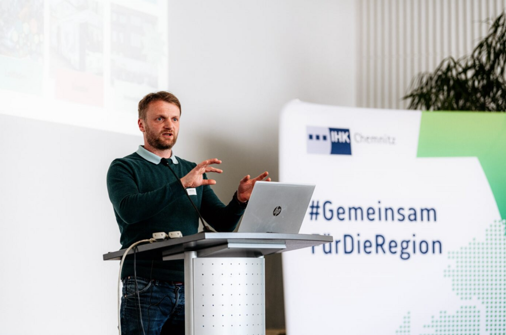 Robert Eckardt steht am Pult und spricht zum Publikum