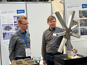 Michael Pfeifer (rechts) erläutert den metallgedruckten Verbindungsknoten für Freiform-Fassaden, ein Kooperationsprojekt mit der Forschungsgruppe FLEX der HTWK Leipzig im Verbundprojekt Saxony5.