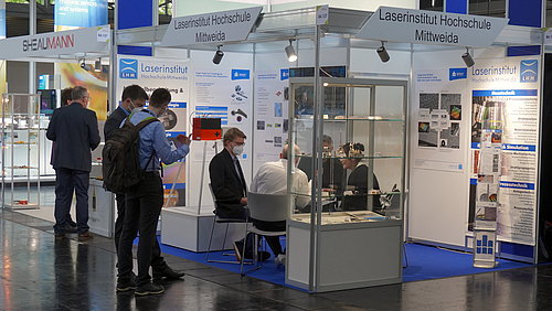 Besucher:innen lassen sich am Messestand beraten