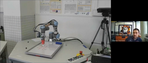 Roboterarm spielt am Tisch Tic-Tac-Toe, Christian Thorman daneben im Bildausschnitt 