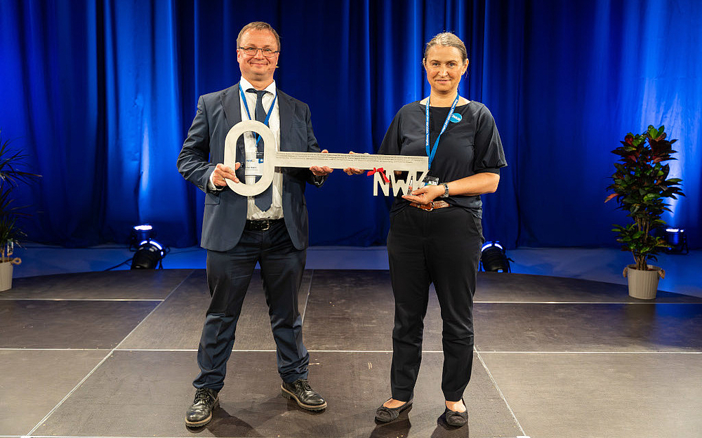 Eine männliche und eine weibliche Person halten einen großen Schlüssel in der Hand