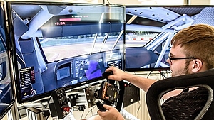 männliche Person sitzt vor gebogenem Monitor und fährt simulativ ein Autorennen
