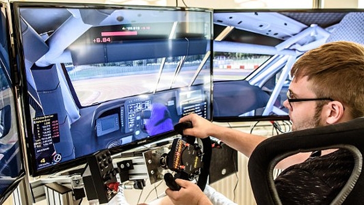 männliche Person sitzt vor gebogenem Monitor und fährt simulativ ein Autorennen