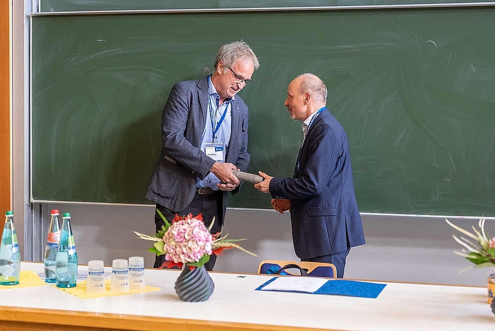 Überreicht: Nach 2017 in der digitalen Variante nun in echt - Prof. Jörg Matthes (rechts) übergibt den Staffelstab für das Forum 2026 an Prof. Jens Bliedtner von der EAH Jena Zwei Männer übergeben den Staffelstab