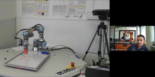 Roboterarm spielt am Tisch Tic-Tac-Toe, Christian Thorman daneben im Bildausschnitt