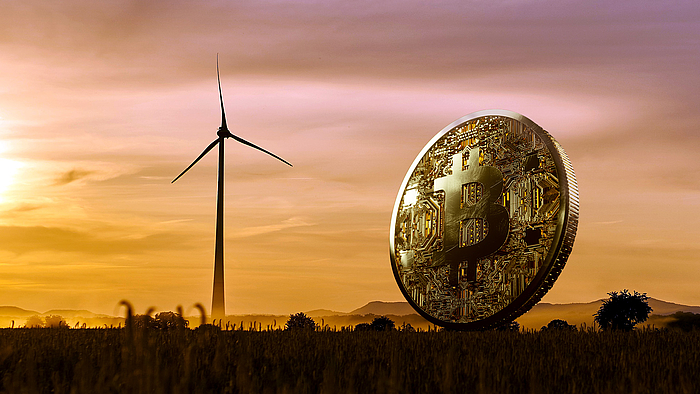 Bitcoin Münze vor Windkraftanlage